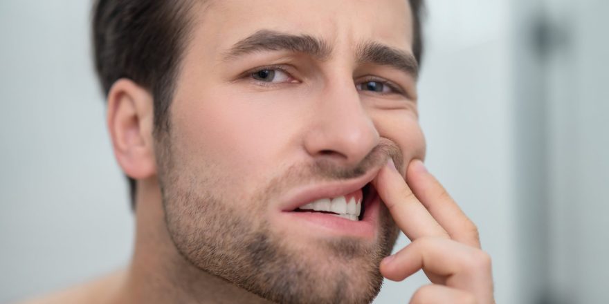 dental-problems-man-checking-his-teeth-looking-disturbed-min