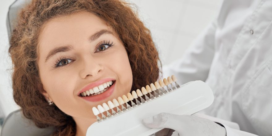 woman-smiling-while-male-dentist-keeping-teeth-color-range-min